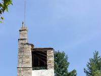 Beaumont- Cévenne ardéchoise  Le clocher, ici vu de profil, est curieux. Il s'agit d' un clocher mur possédant deux cloches. Ici à l'arrière du clocher se trouve un petit abri couvert