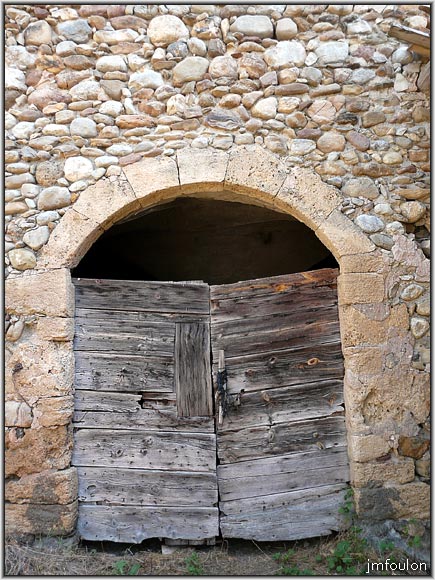 nibles-35web.jpg - Porte de l'étable. A l'intérieur on peut apercevoir au travers de la porte fermée une voute à croisée d'ogives, ainsi qu'une voiture à cheval