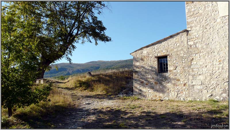 eglise-09web.jpg - Petite pièce à un seul pan de toiture adossée à la façade ouest de l'église. Au loin, la montagne de Mare (1822 m)